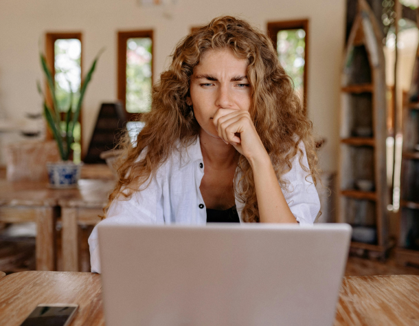 woman working on laptop, looks confused, trying to solve a problem